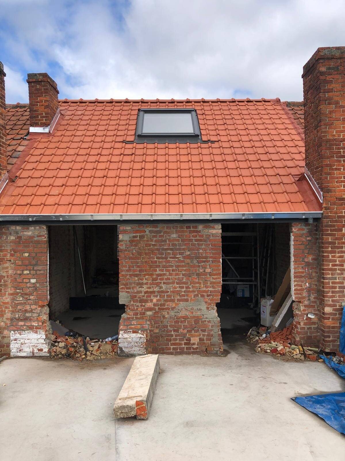 Nieuw hellend dak met dakpannen en een Velux dakraam op een gerenoveerde gevel.