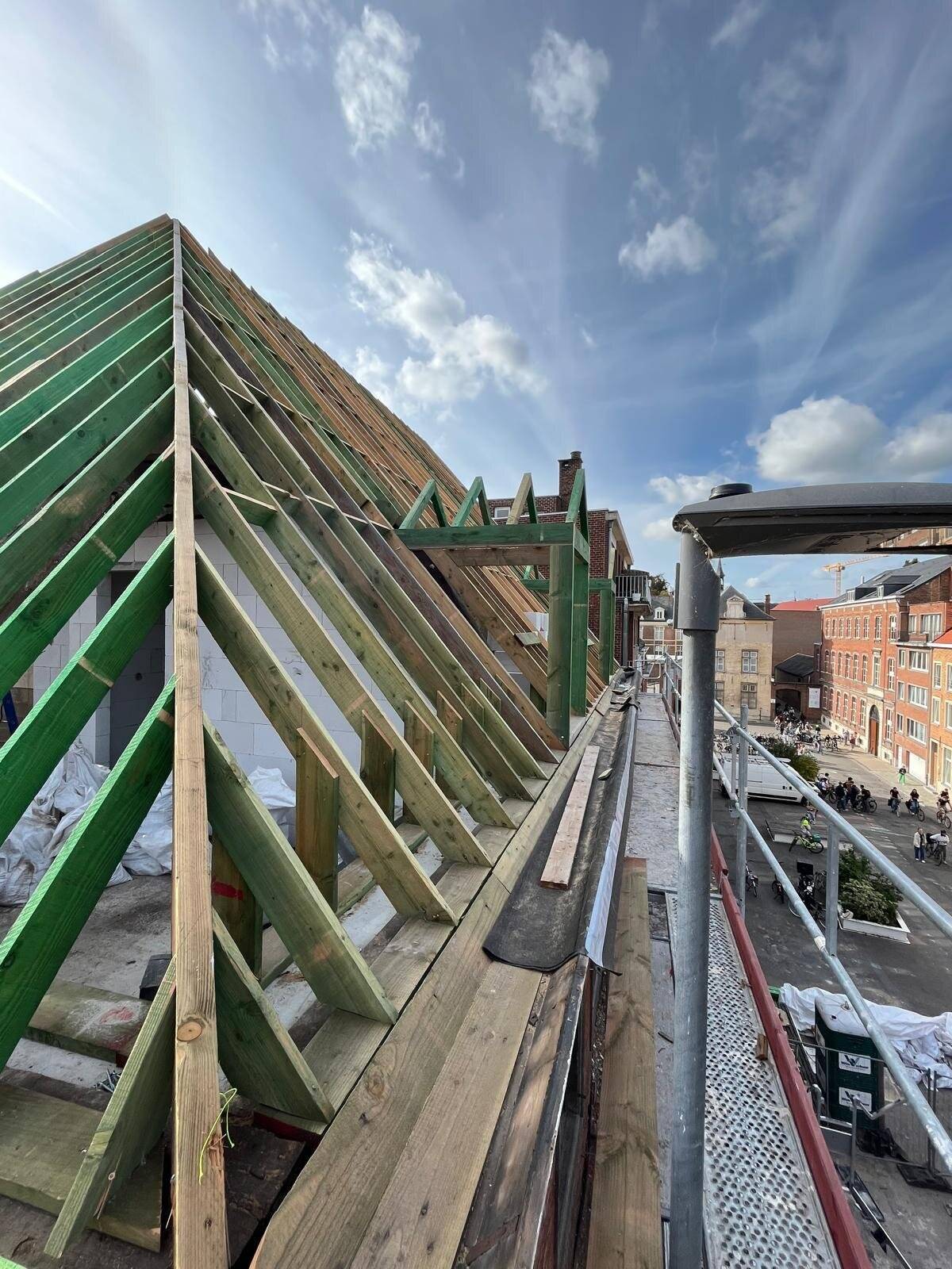Nieuwe houten dakconstructie van een hellend dak, gezien vanaf steigers.