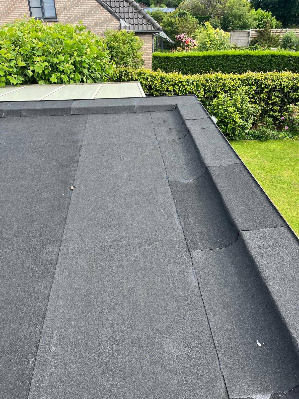 Detail van de rand en afvoer van een plat dak met bitumen.